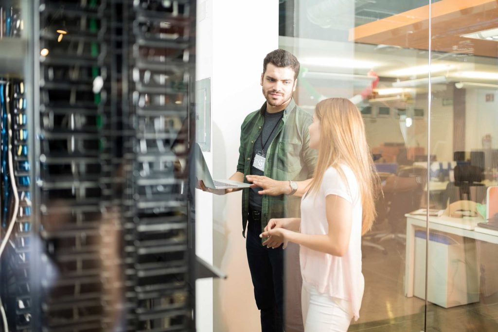Controle de ponto em nuvem 1 two business people standing server room with laptop discussing Master Tecnologias